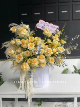 Góc 1 của Bình vàng kem thanh nhã — Các bông hoa vàng kem được cắm xòe ngang trong bình trắng có gân