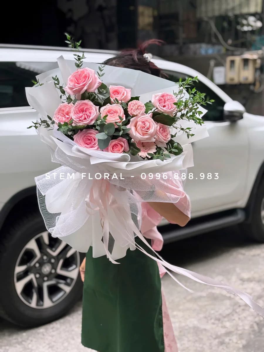 Bó hồng vườn nhỏ — Hoa hồng phấn phối lá xanh đậm và các nhánh nhỏ màu sáng, được bó trong giấy trắng hồng