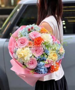 Góc 1 của Ngày vui nhiều sắc hoa — Hoa hồng hồng và vàng kem phối cẩm tú cầu xanh, điểm cẩm chướng cam, đồng tiền hồng và nhánh hoa nhỏ trắng