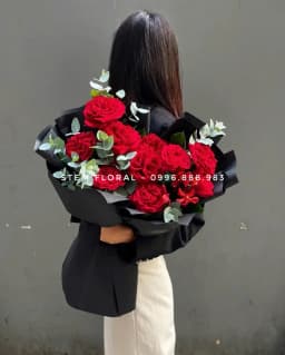 Góc 1 của Hồng thắm kiêu hãnh — Hoa hồng đỏ phối lá xanh trong giấy đen gọn quanh phần cành