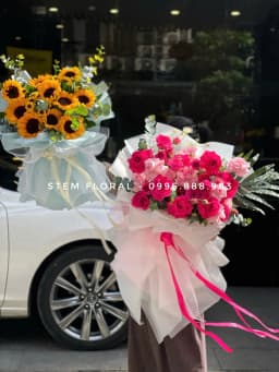 Góc 2 của Hồng đỏ tinh khôi — Hoa hồng đỏ nổi bật trên lớp giấy trắng hồng xòe rộng, xen lá xanh và những nhánh hoa nhỏ trắng