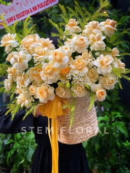 Góc 2 của Giỏ hoa màu nắng — Hoa kem vàng tạo thành dáng xòe rộng trên giỏ có quai, xen lá xanh và các nhánh vàng mảnh