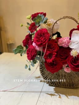 Góc 2 của Giỏ hồng đỏ — Hoa đỏ đậm được xếp thành nhiều tầng quanh quai giỏ mây, xen cánh lan trắng và lá xanh