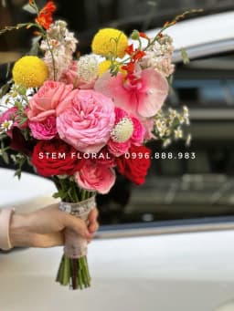 Góc 3 của Hồng rực cầm tay — Bó cầm tay để lộ phần cuống, phối hoa hồng sắc hồng đỏ cùng những điểm vàng tròn và hoa nhỏ